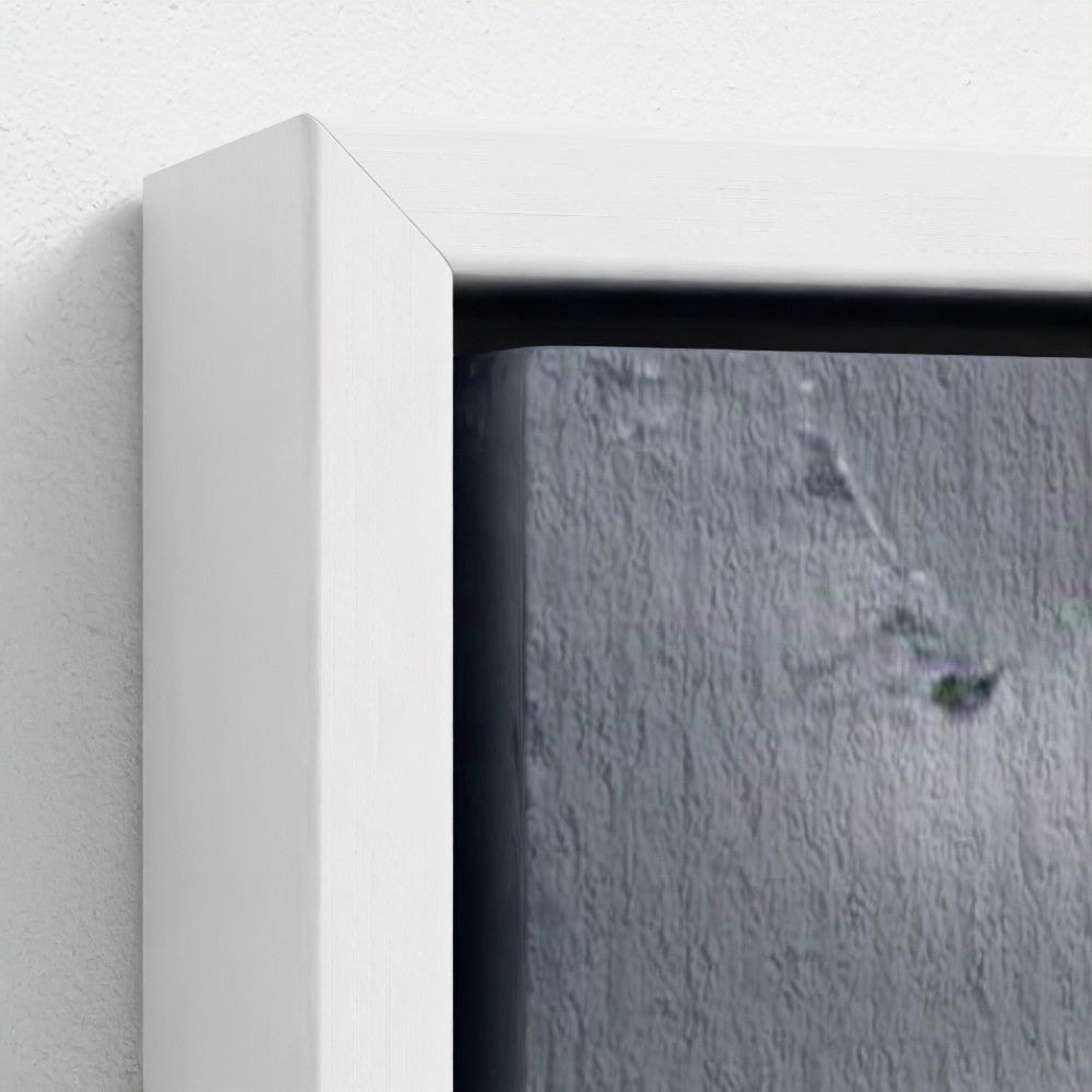 Close-up of a framed picture with a white border on a textured gray wall.