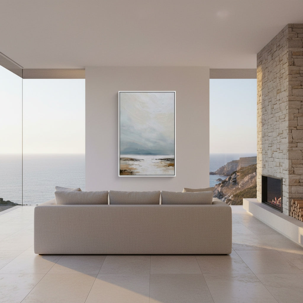 Modern living room with a sofa, abstract painting, and fireplace overlooking a scenic view.