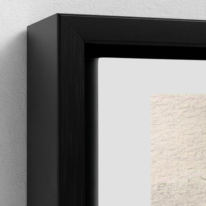 Close-up of a black framed picture on a light gray wall.
