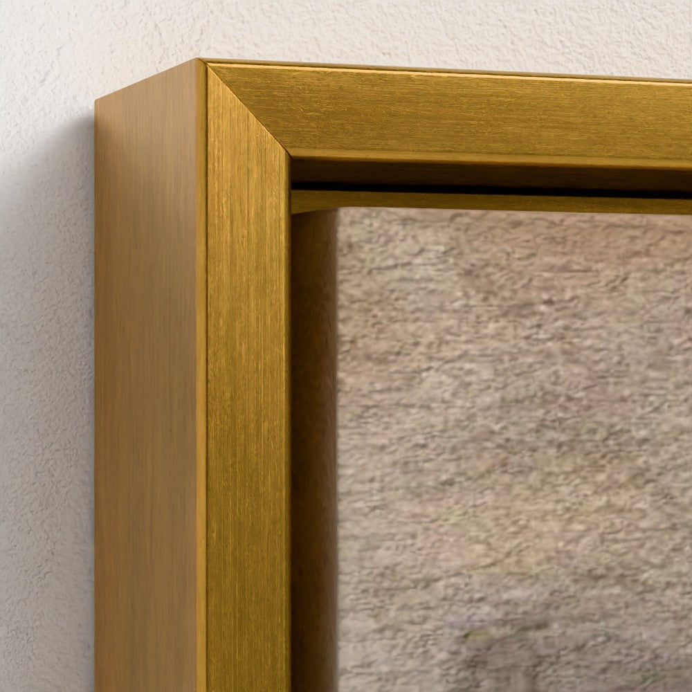 Close-up of a gold framed mirror on a textured wall.