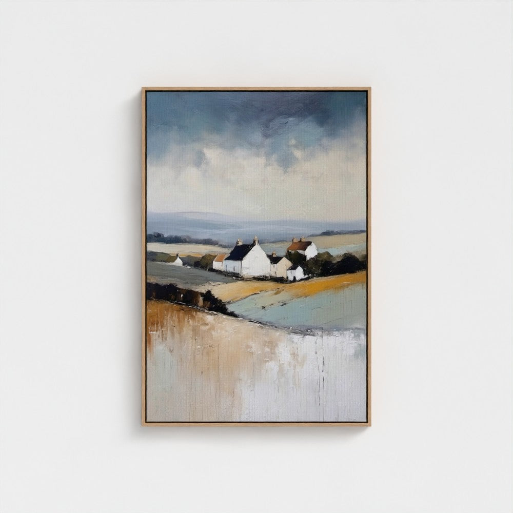 Framed artwork of a landscape with houses and fields on a white wall