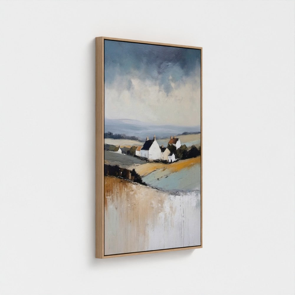 Framed artwork of a landscape with houses and fields on a white wall