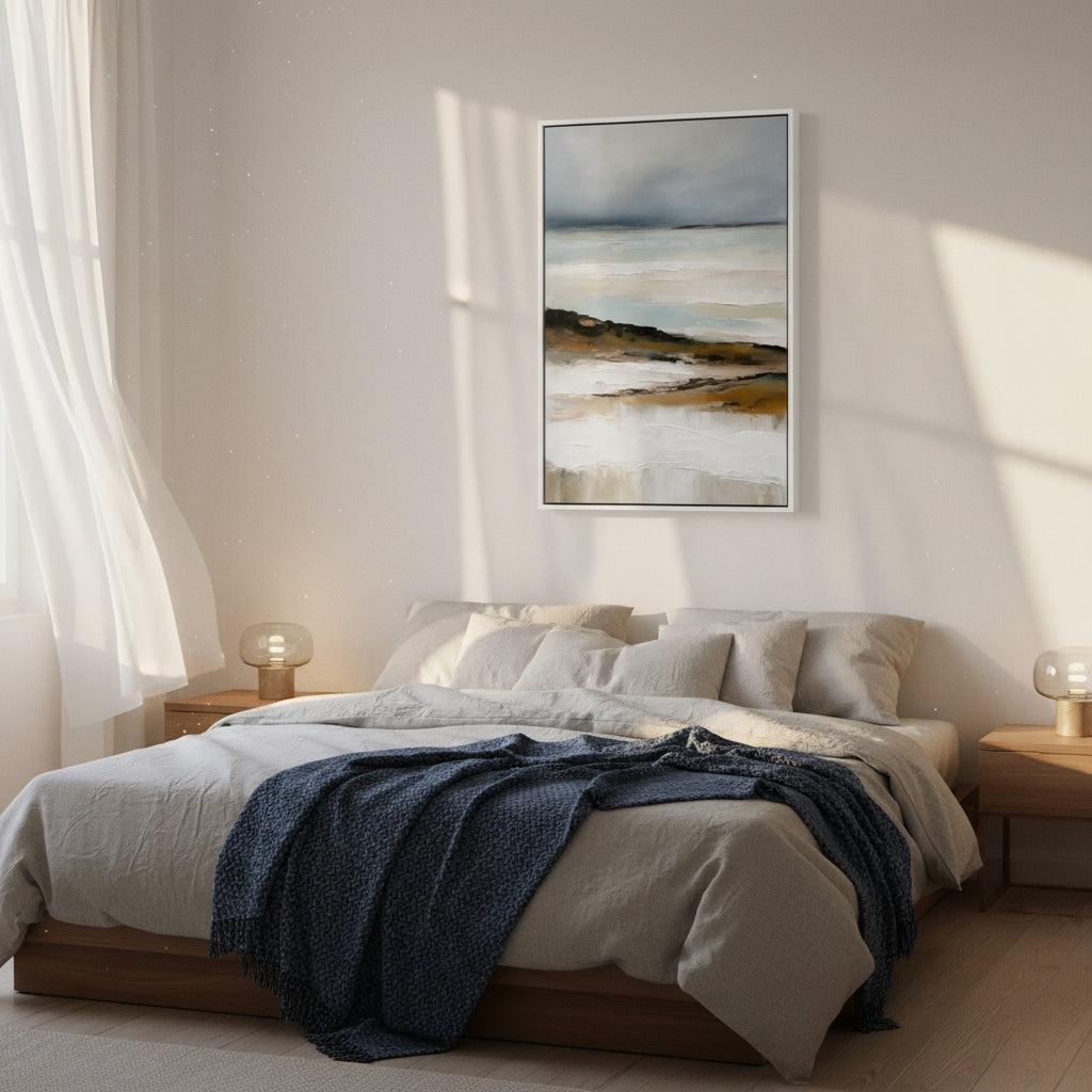 Bedroom with a bed, blue blanket, and framed artwork on the wall.