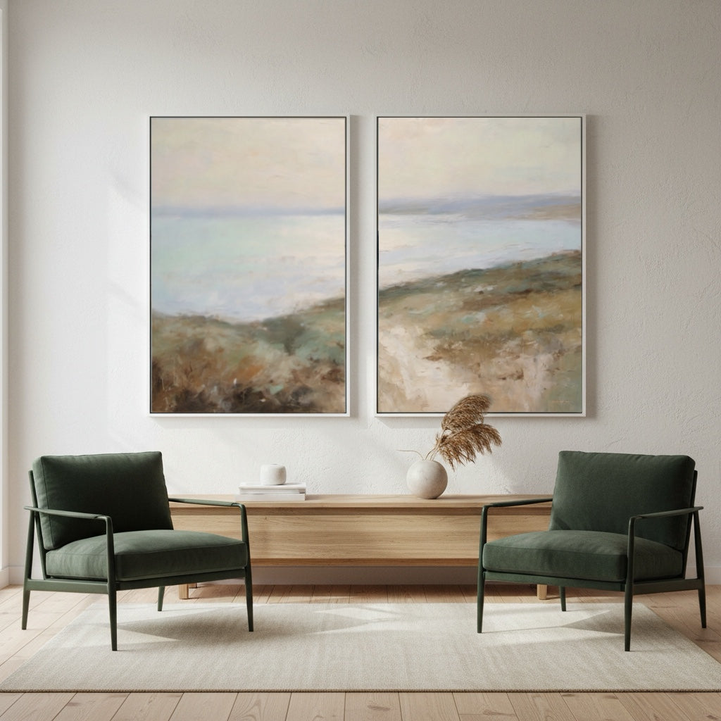 Two green armchairs in a living room with two landscape paintings on the wall.