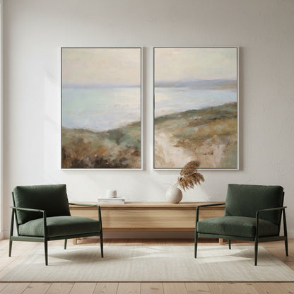 Two green armchairs in a living room with two landscape paintings on the wall.