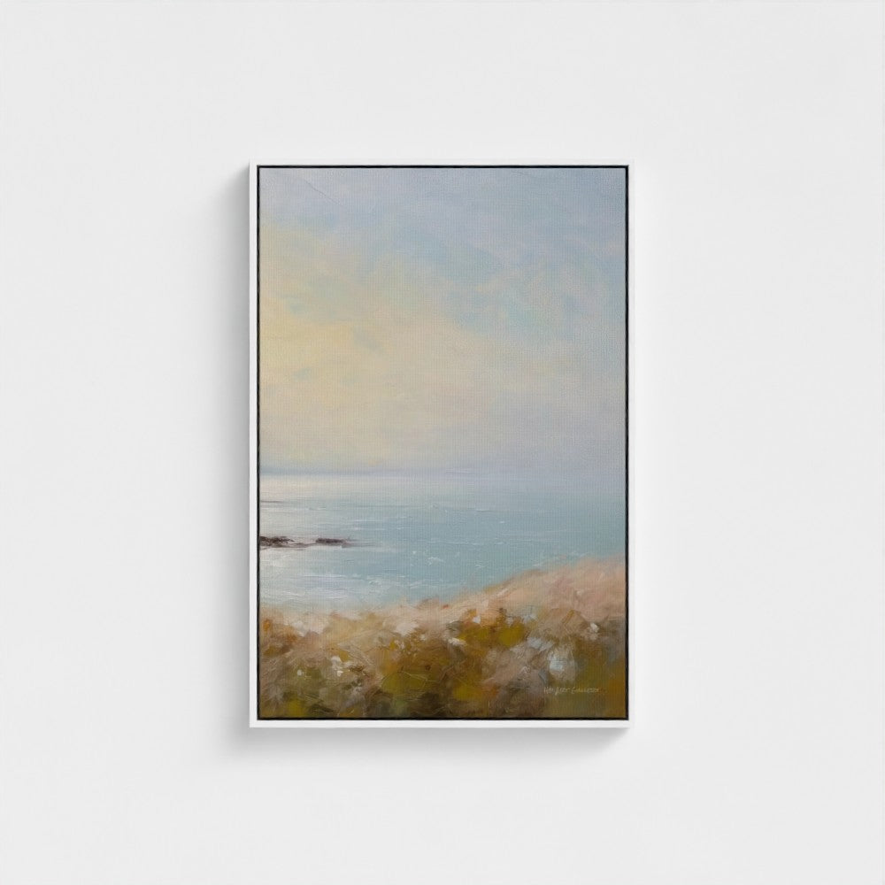 Framed artwork of a coastal landscape with a blue sky and ocean.