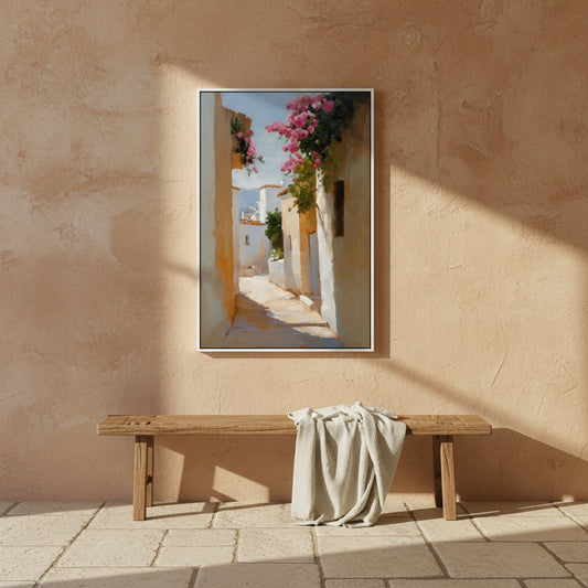 Framed artwork of a sunlit street scene with flowers on a textured wall above a wooden bench.