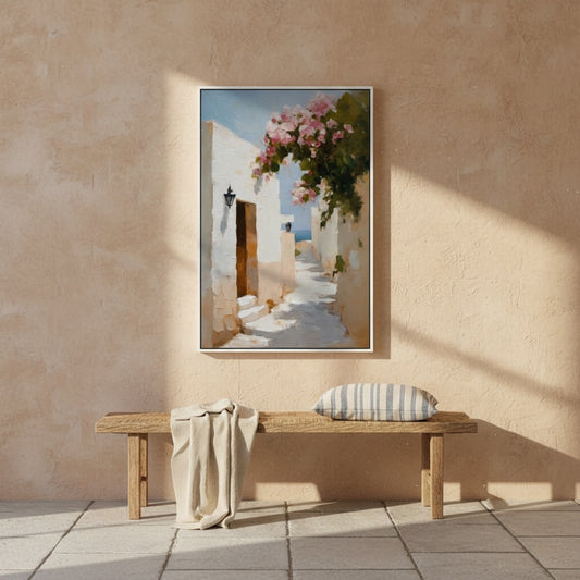 Framed artwork of a mediterranean alley scene with flowers on a beige wall above a wooden bench.
