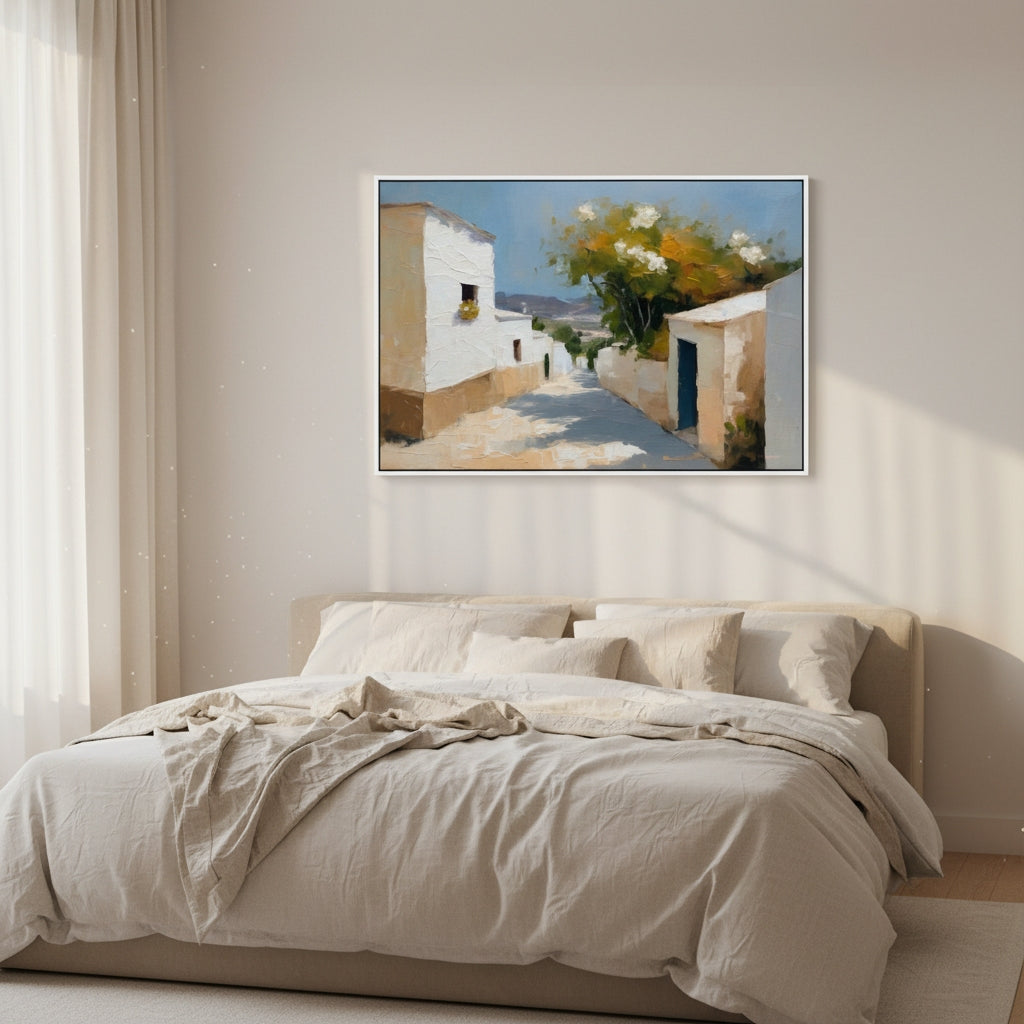 Framed artwork of a Mediterranean street scene above a bed in a bedroom.