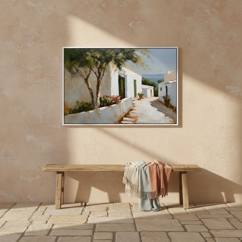Framed painting of a coastal scene on a beige wall above a wooden bench with cloths.