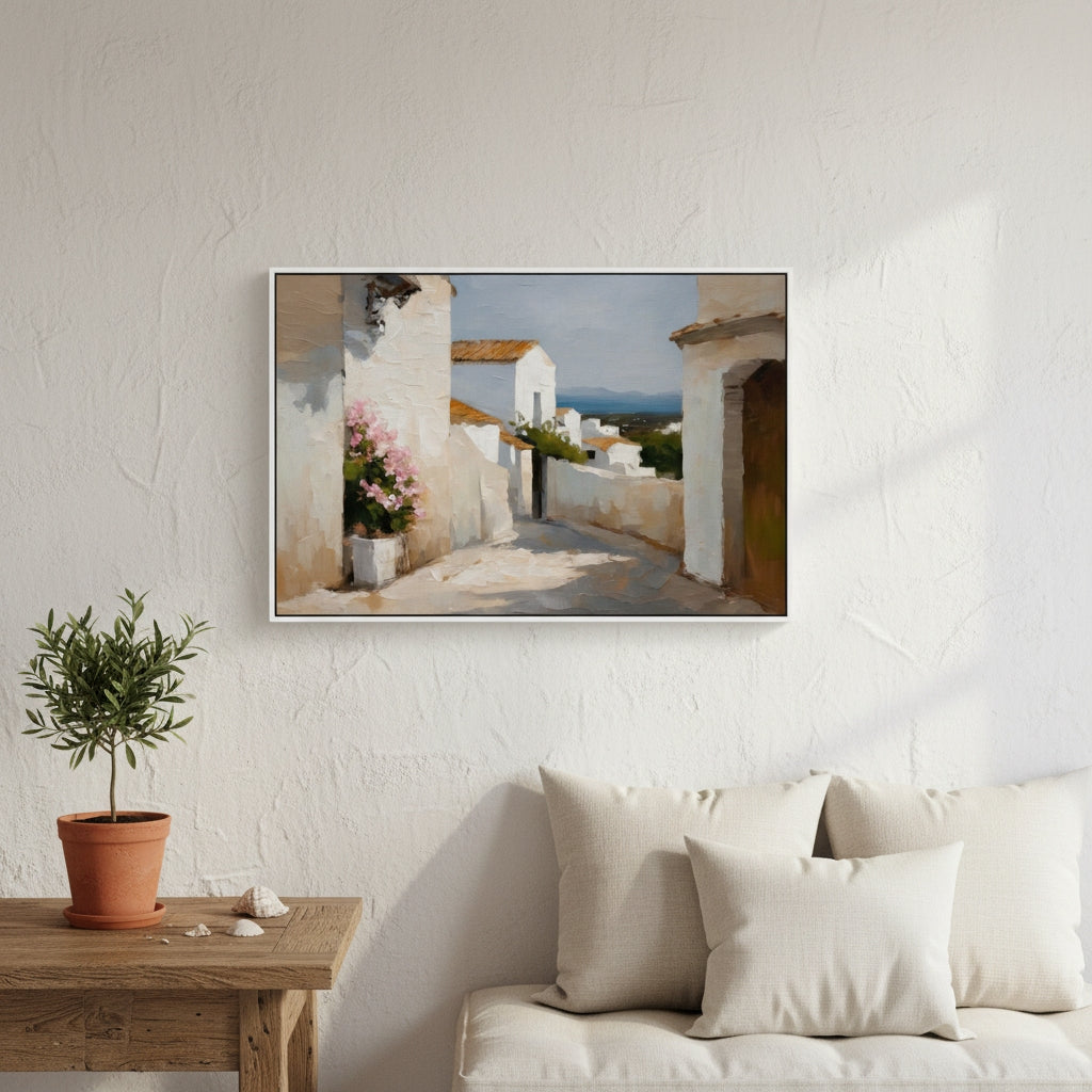 Framed artwork of a scenic village scene above a white sofa with a wooden table and plant.